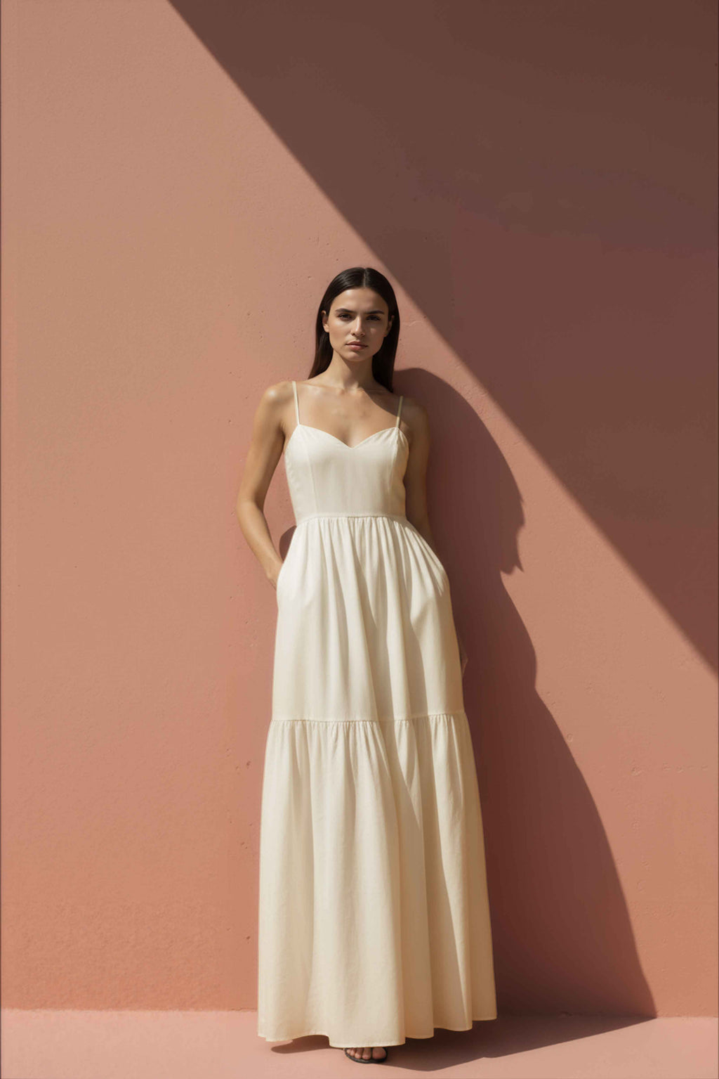 Woman wearing a white cotton dress against a pink wall