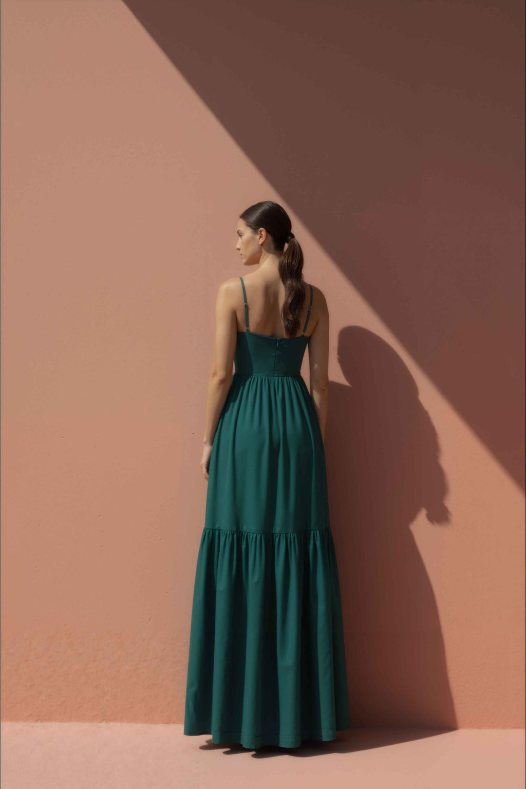 Woman wearing a green maxi cotton  dress against a pink background
