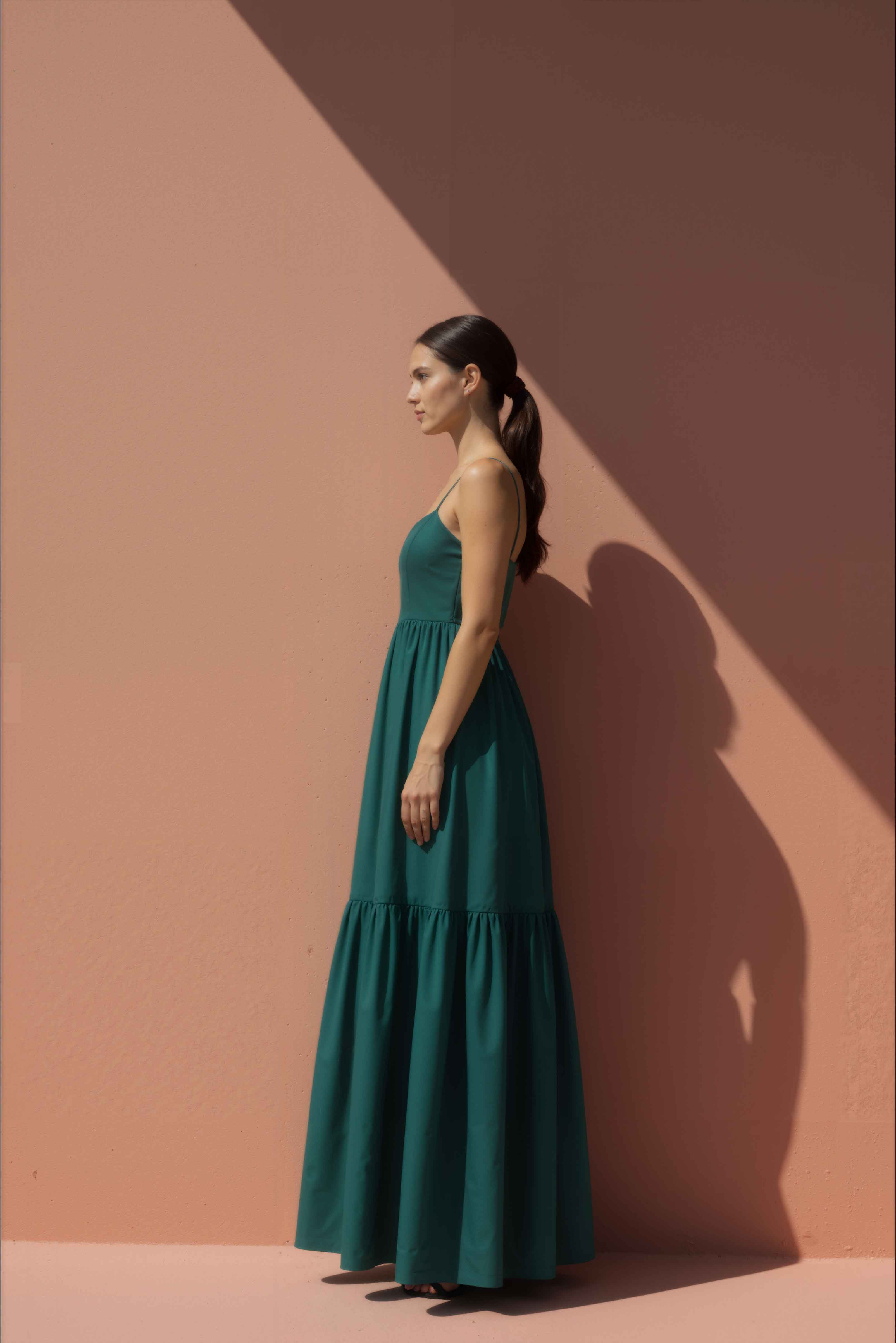 Woman wearing a green maxi cotton  dress against a pink background