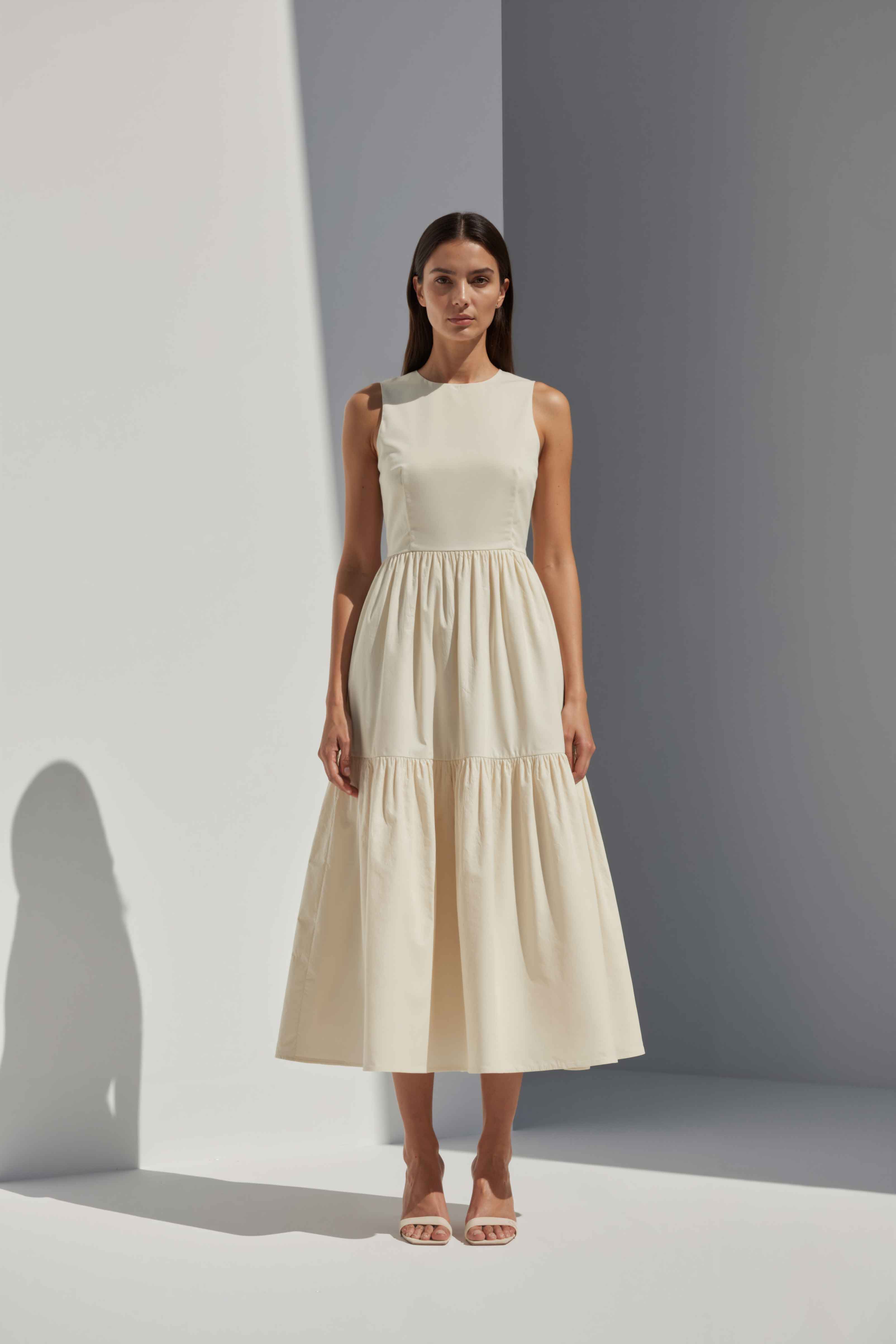 Anasua The Forme Edit Poplin Cotton Midi Dress in Halo Cream, a structured sleeveless cotton midi dress with a tiered skirt, photographed under natural sunlight.
