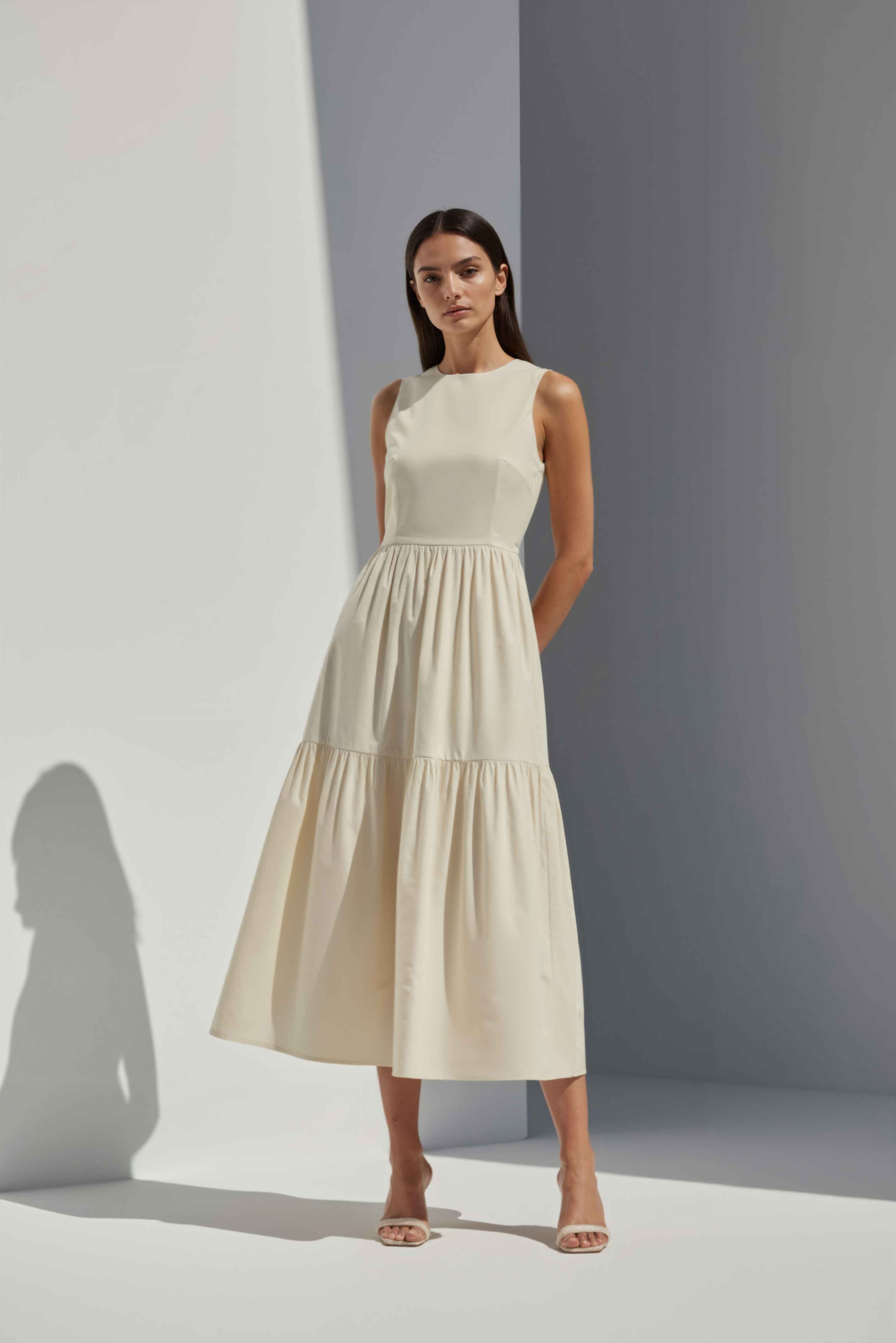 Anasua The Forme Edit Poplin Cotton Midi Dress in Halo Cream, a structured sleeveless cotton midi dress with a tiered skirt, photographed under natural sunlight.