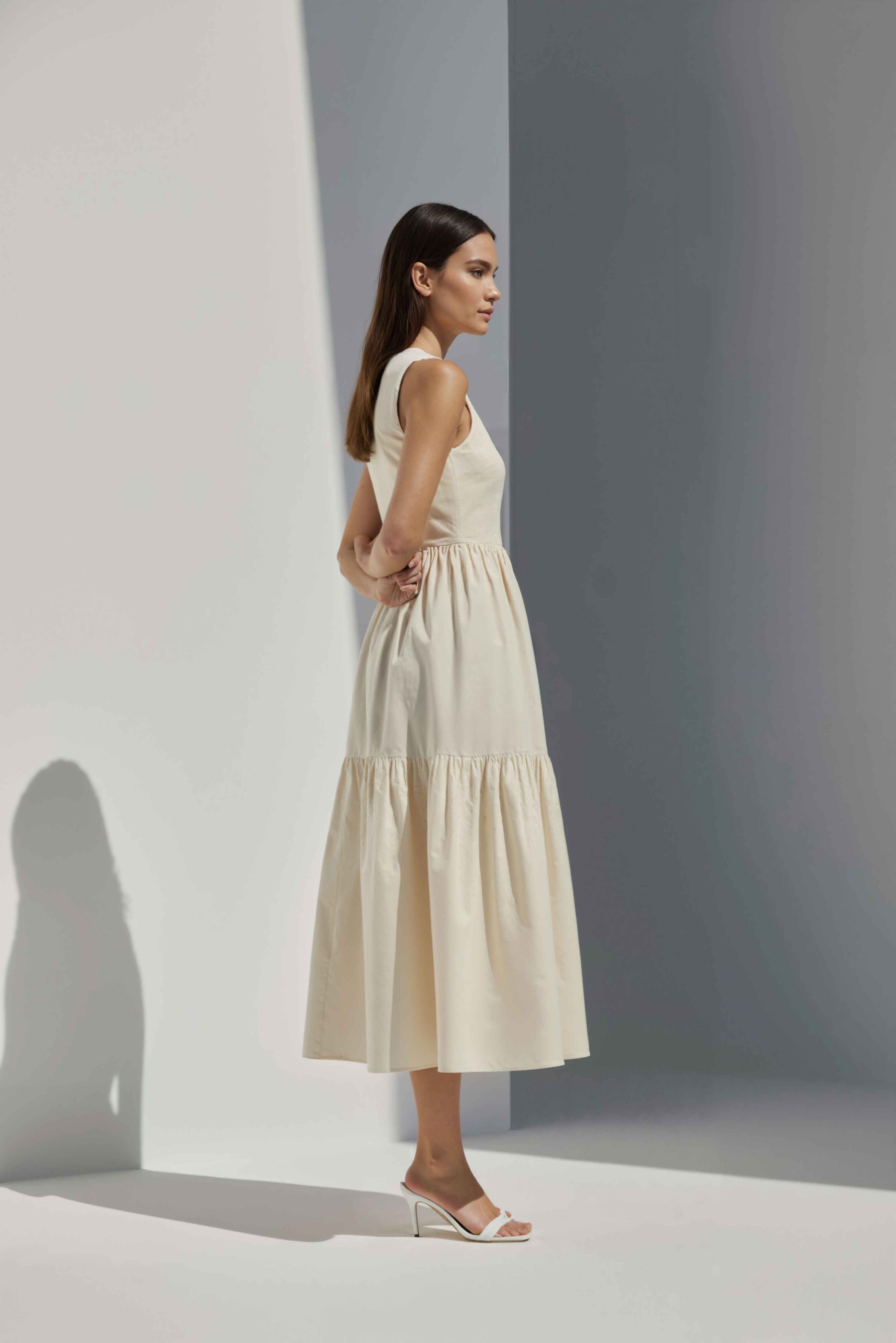 Anasua The Forme Edit Poplin Cotton Midi Dress in Halo Cream, a structured sleeveless cotton midi dress with a tiered skirt, photographed under natural sunlight.